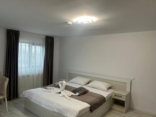 a bedroom with a large bed with white sheets at Pensiunea La Cazemata Bucov in Satu Bucovei