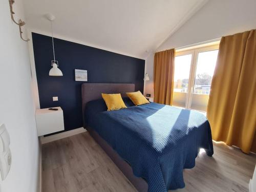 Un dormitorio con una cama azul con almohadas amarillas en BADEBUDE 3 Ferienhaus im Hampton Style, en Oldenburg in Holstein