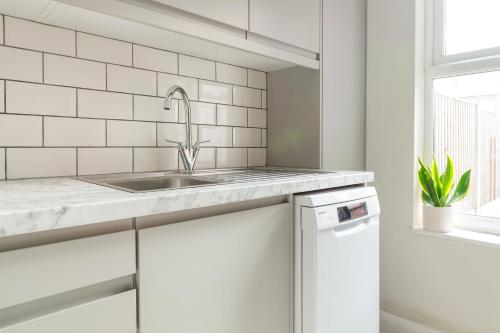 a white kitchen with a sink and a window at Lovely 2 Bedroom House - Free Parking - Accommodation near QMC Hospital & University of Nottingham - Suitable for Short Stays & Long Stays in Nottingham