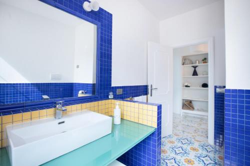 a blue tiled bathroom with a sink and a mirror at Villa Il Canto delle Sirene in Marciano