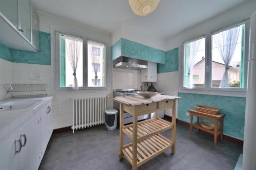 - une cuisine avec des murs et des fenêtres verts et blancs dans l'établissement Luchon Maison Flor, à Luchon