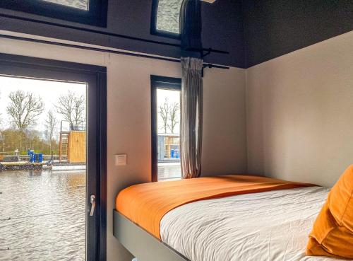een slaapkamer met een bed en een raam bij Houseboat orange Sneekermeer in Offingawier