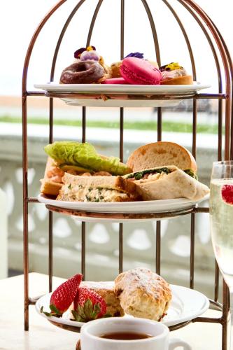 two tiers of sandwiches and pastries on plates with a glass of wine at The Burlington in Worthing