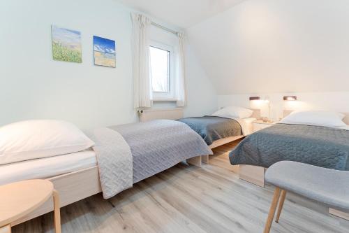 een slaapkamer met 3 bedden en een raam bij Wohnpark Heisterbusch Ferienhaus 13d in Kellenhusen