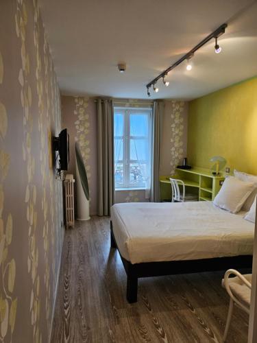 1 dormitorio con cama y escritorio. en Hotel du Saumon, Verneuil sur Avre, en Verneuil d'Avre et d'Iton