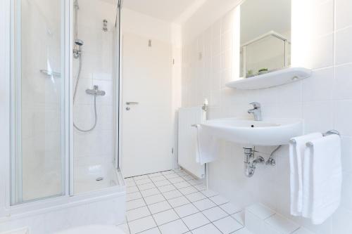 een witte badkamer met een wastafel en een douche bij Wohnpark Heisterbusch Ferienhaus 13d in Kellenhusen