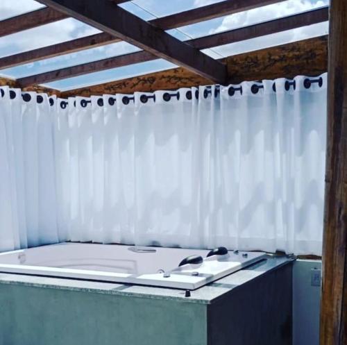 a room with a white shower curtain and a tub at Chale Vista Encantada in Lavras Novas