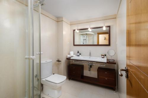 uma casa de banho com um WC, um lavatório e um espelho. em Nordik Apartments Urban - Playa Virginia "Hanko" em Málaga