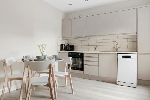 a kitchen with white cabinets and a table and chairs at Lovely 2 Bedroom House - Free Parking - Accommodation near QMC Hospital & University of Nottingham - Suitable for Short Stays & Long Stays in Nottingham