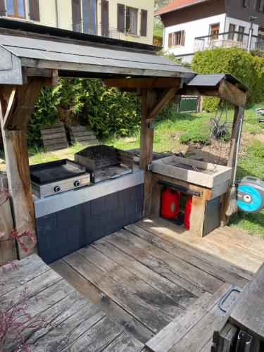 a barbecue grill on a deck in a yard at Joli logement avec terrasse La Cigale 6 à 8 personnes in Orbey