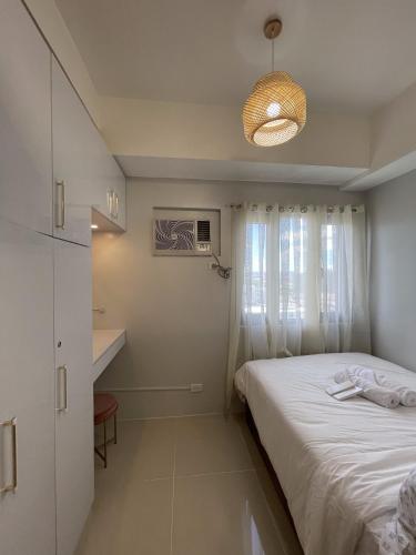 Habitación pequeña con cama y ventana en Grass Residences Charming Staycation, en Manila