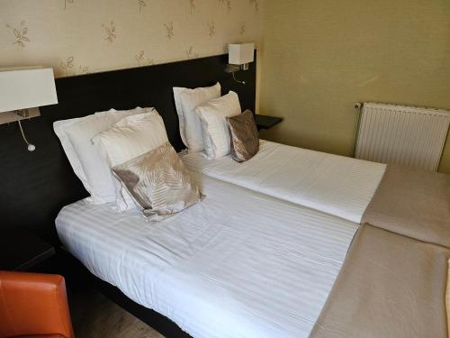 a bed with white sheets and pillows at Hotel du Saumon, Verneuil sur Avre in Verneuil d’Avre et d’Iton
