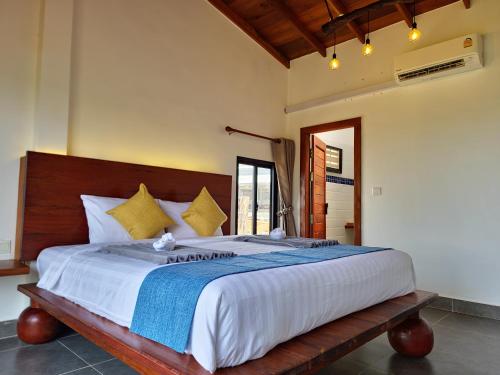 a bedroom with a large bed with a wooden headboard at PIDA COFFEE FARM LODGE in Phumĭ Pu Pal