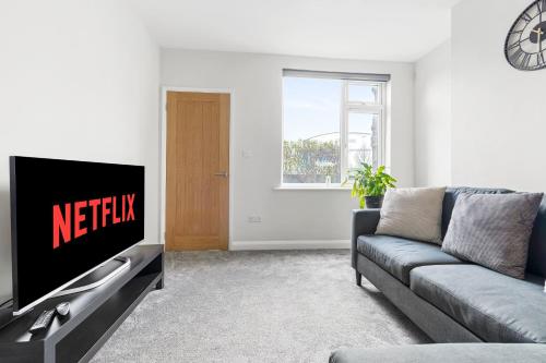 a living room with a couch and a tv at Lovely 2 Bedroom House - Free Parking - Accommodation near QMC Hospital & University of Nottingham - Suitable for Short Stays & Long Stays in Nottingham