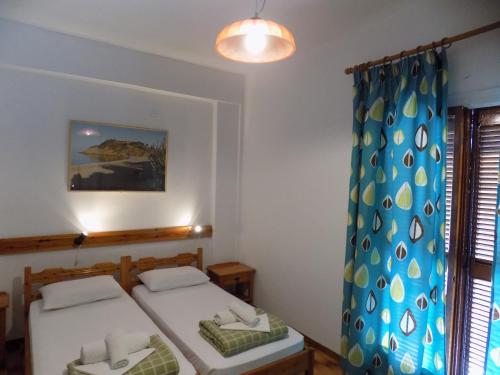 a bedroom with two beds and a blue curtain at PensionMargaritaKotroniSkiathos in Skiathos Town