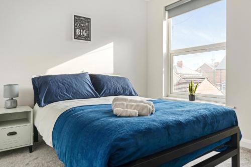 a bedroom with a bed with a blue blanket and a window at Lovely 2 Bedroom House - Free Parking - Accommodation near QMC Hospital & University of Nottingham - Suitable for Short Stays & Long Stays in Nottingham