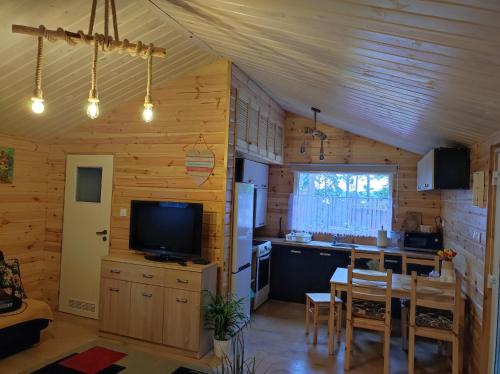 eine Küche und ein Esszimmer mit einem Tisch und einem TV in der Unterkunft Domek pod sosnami in Grodziczno