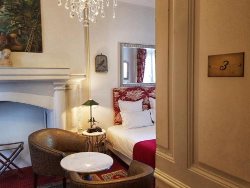 a bedroom with a bed and a table and a chandelier at Le Clos d'Amboise in Amboise