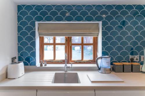um balcão de cozinha com um lavatório e uma janela em Old Dairy Cottage - Cosy and Luxurious! em Buckinghamshire