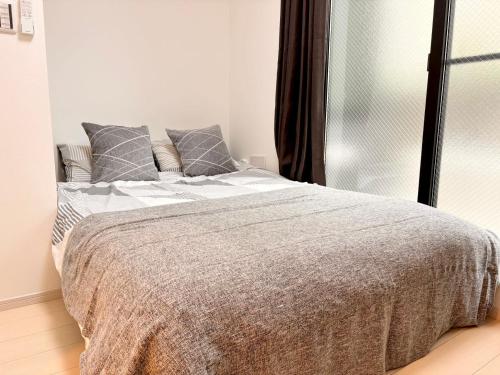 Dormitorio blanco con cama con almohadas grises en IXO Ts1 en Tokio