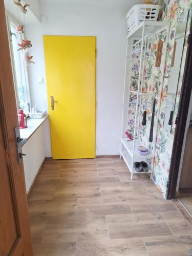 a yellow door in a room with a floor at Lesný domček in Hunisky