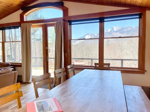 a dining room with a table and views of mountains at Algonquin Mountain Chalet in Wilmington