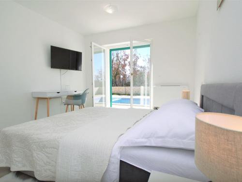 a white bedroom with a bed and a desk at Holiday Home Skelin by Interhome in Drinovci
