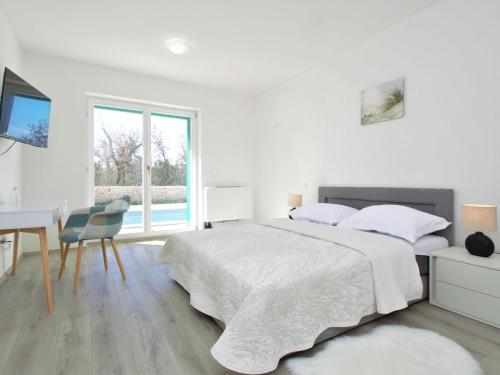 a white bedroom with a bed and a desk at Holiday Home Skelin by Interhome in Drinovci