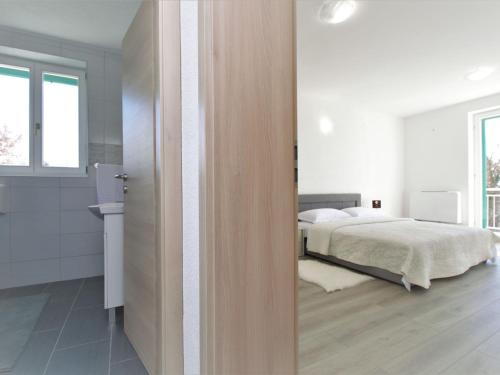 a white bedroom with a bed and a window at Holiday Home Skelin by Interhome in Drinovci