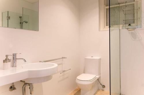 a white bathroom with a toilet and a sink at Dungawon - Beachfront in Sydney