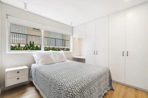 a white bedroom with a bed and a window at Aqua Blu - Prized Position in Sydney