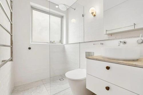 a white bathroom with a toilet and a sink at Aqua Blu - Prized Position in Sydney