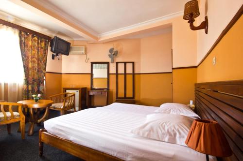 a bedroom with a large bed and a table at Anjary Hotel Antananarivo in Antananarivo