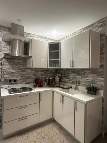 a kitchen with white cabinets and a sink at Rose 3 in Al Khobar