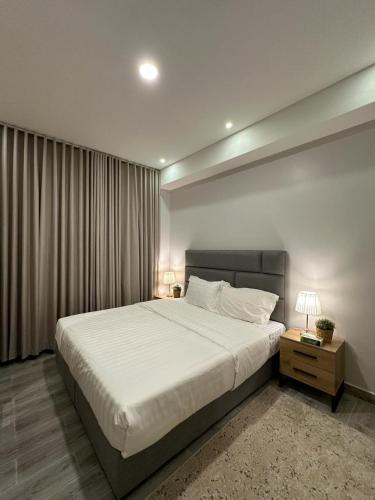 a bedroom with a large white bed and a night stand at Rose 3 in Al Khobar