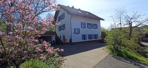 ein großes weißes Haus mit blauen Fenstern und Blumen in der Unterkunft BR-Ferienwohnung Brombachtal in Langen-Brombach