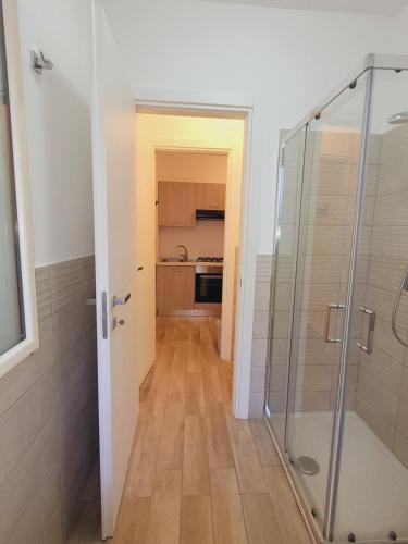 a bathroom with a glass shower and a kitchen at HOUSE AIRPORT VINCENZO APP.7 - APP.8 in Catania