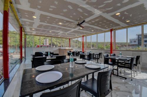a restaurant with tables and chairs and large windows at The Greenpark Retreat, Mahabaleshwar in Mahabaleshwar