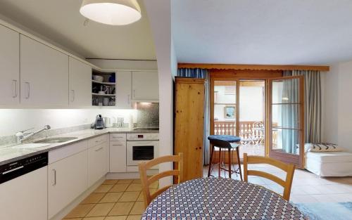 uma cozinha com armários brancos e uma mesa e cadeiras em Nina - b42985 em Celerina