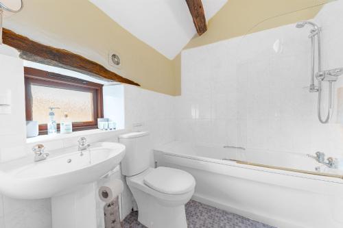 a white bathroom with a toilet and a sink at Damson Cottage in Waberthwaite