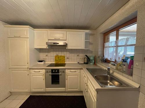 a kitchen with white cabinets and a sink and a window at Haus Rosa in Sankt Johann