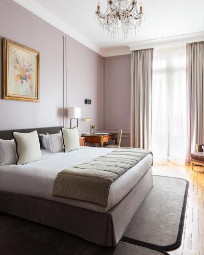 a bedroom with a large bed and a chandelier at Hôtel Lancaster Paris Champs-Elysées in Paris