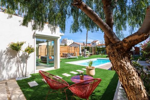 un jardin avec une table et des chaises à côté d'un arbre dans l'établissement VILLA COTE SUD VI4402 By Riviera Holiday Homes, à Cagnes-sur-Mer