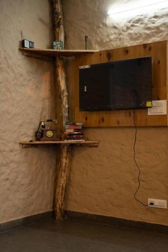 a wall with a shelf with a television on it at Rustic Roots Home Stay in Nagar