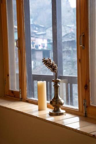 a candle sitting on a window sill next to a window at Rustic Roots Home Stay in Nagar