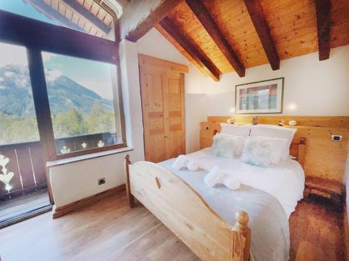 una camera da letto con un letto grande e una grande finestra di Spacieux Chalet 19pers, Piscine, Jacuzzi, Sauna & Salle de Jeux a Champagny-en-Vanoise