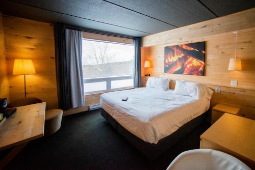 ein Schlafzimmer mit einem großen Bett und einem großen Fenster in der Unterkunft Hotel de l'Horizon in Sutton