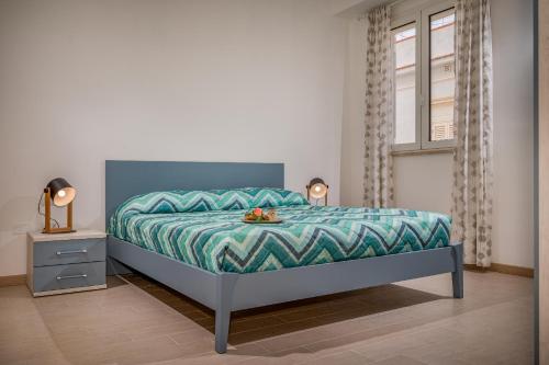 een slaapkamer met een bed met een blauwe en groene sprei bij Appartamento Mare Blu a pochi passi dal mare in Balestrate