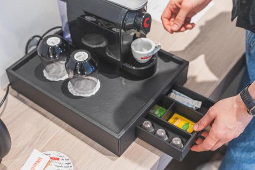 a person is making a coffee in a coffee machine at Downtown Suites by Athens Tower Hotel in Athens