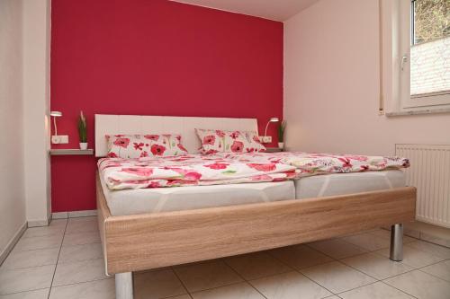 a bed in a bedroom with a red wall at Ferienwohnung Bruttel in Gaienhofen